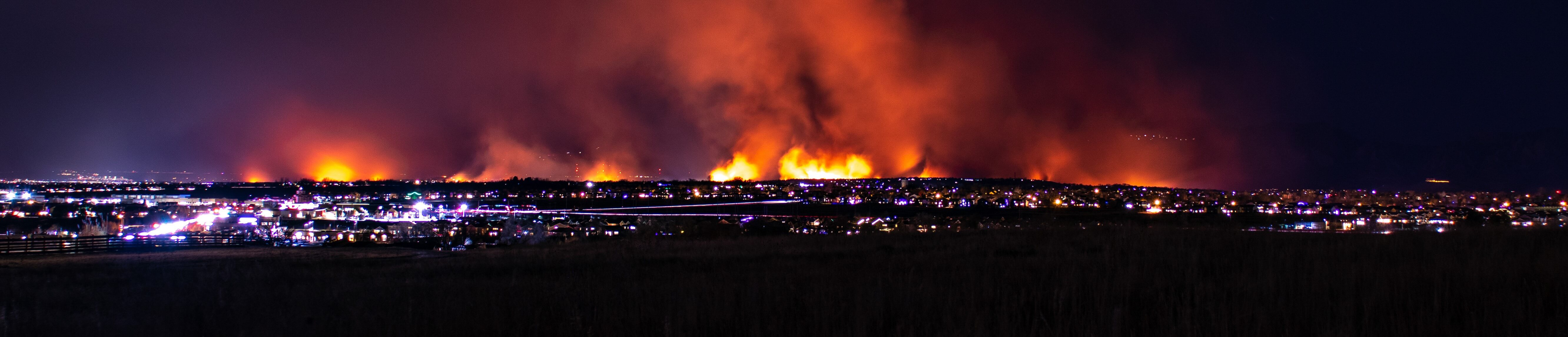 Panoramic view of the Marshall Fire burning near Boulder, Colorado, with intense flames lighting up the night sky.