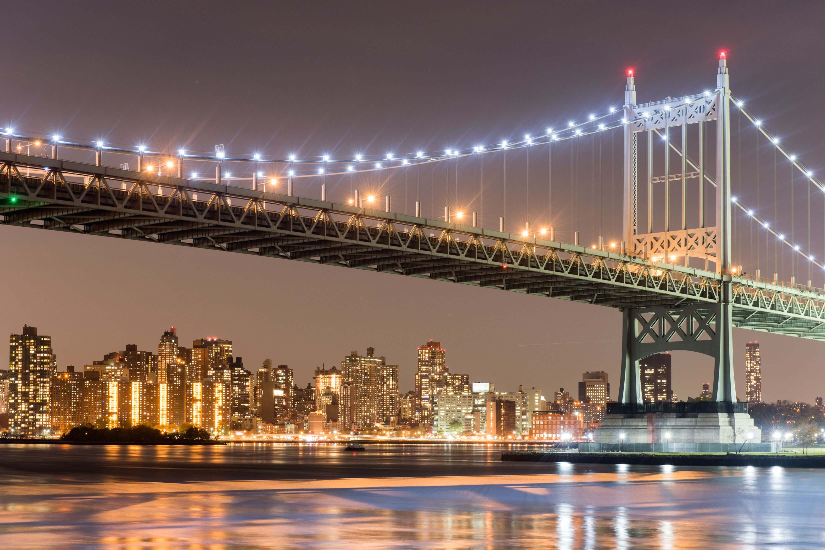 Illuminated RFK Bridge at night, spanning the East River with the New York City skyline in the background. Illuminated RFK Bridge at night, spanning the East River with the New York City skyline in the background.